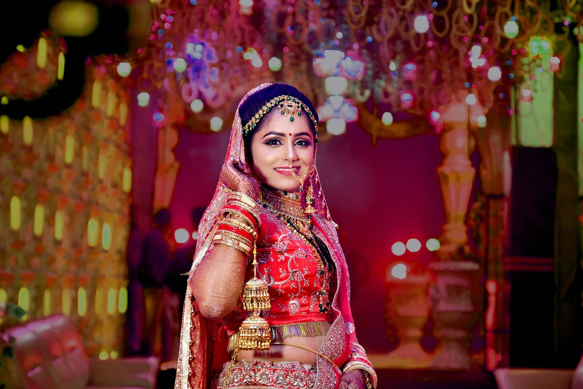 A bride in red and gold beneath warm decorative lights