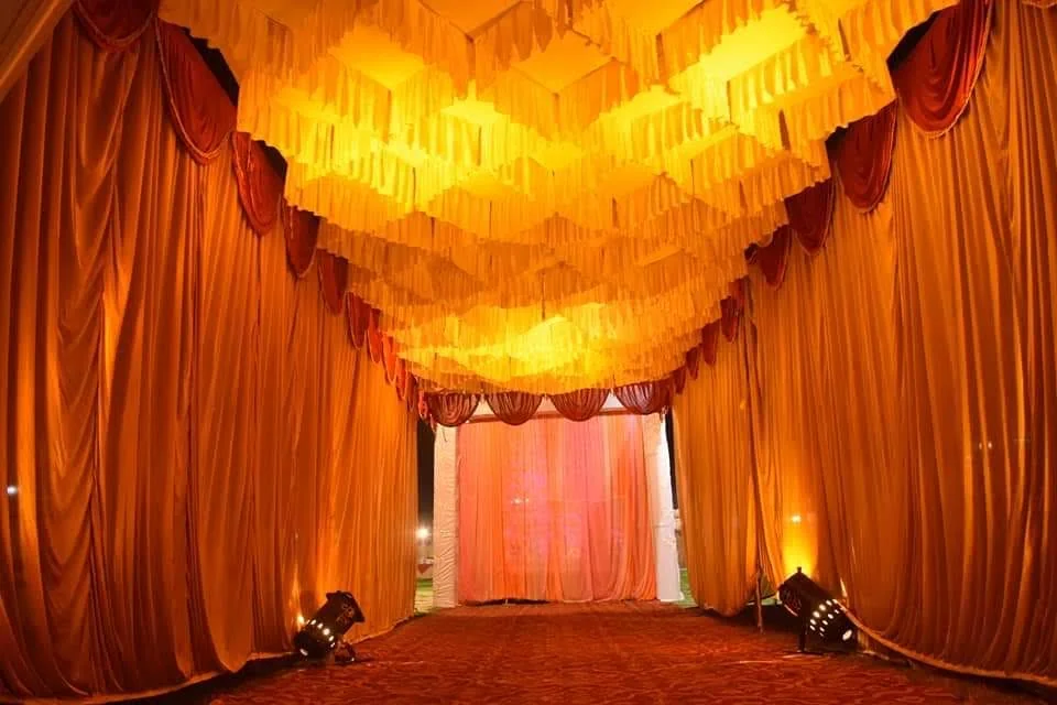 An event entrance draped in orange fabric and lit in warm gold